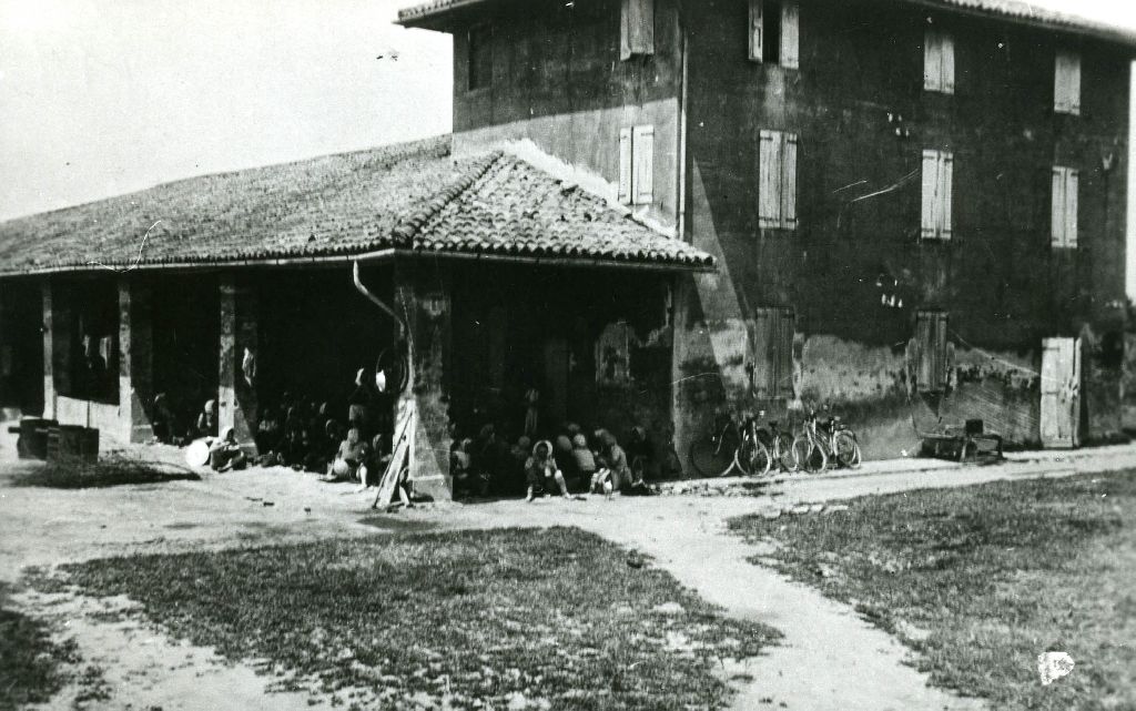 Gruppo di mondine della Cooperativa Lavoratori della terra di Bentivoglio (BO), riprese durante la pausa per il pranzo, sotto un portico di una casa colonica
